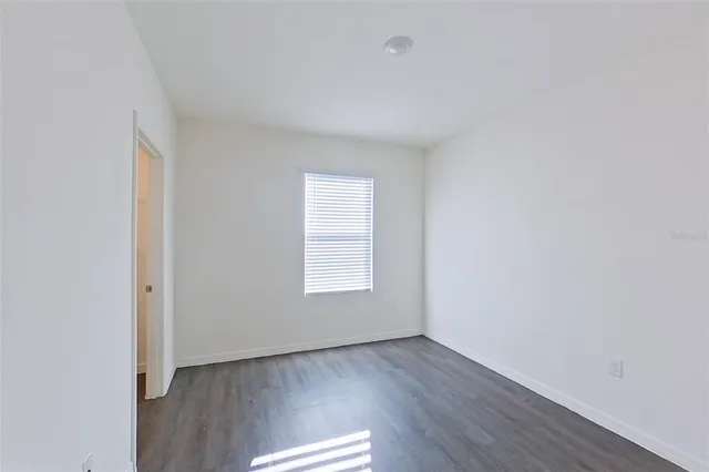 a view of an empty room with wooden floor and window