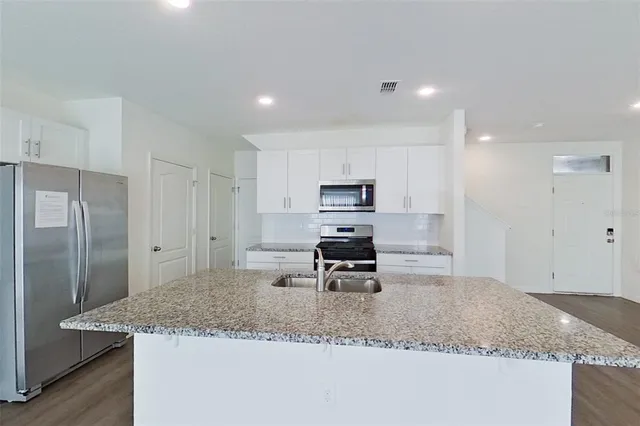 a kitchen with stainless steel appliances granite countertop a sink refrigerator and cabinets