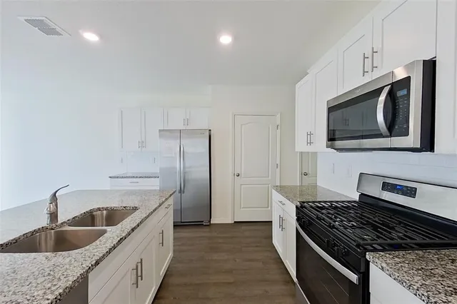 a kitchen with stainless steel appliances granite countertop a sink stove and refrigerator