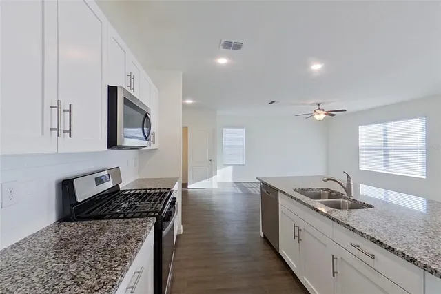 a kitchen with granite countertop a sink stove and cabinets