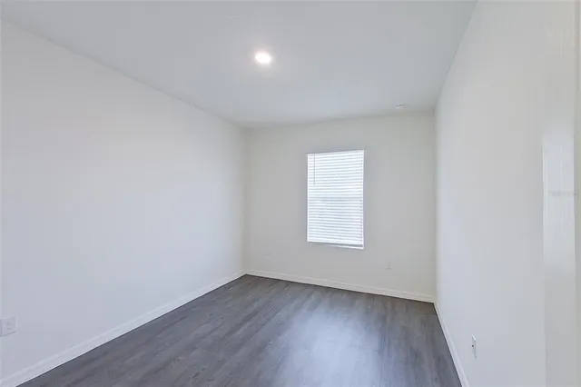 an empty room with wooden floor and window
