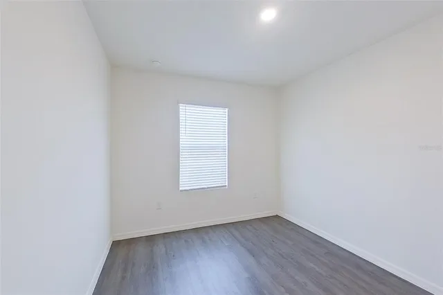 an empty room with wooden floor and window