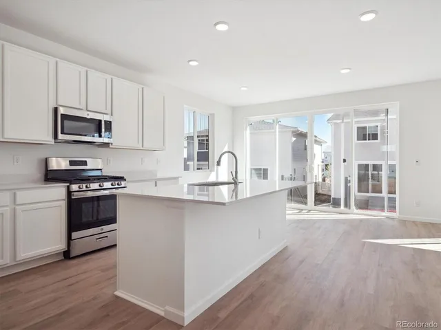 a kitchen with stainless steel appliances a sink cabinets and wooden floor