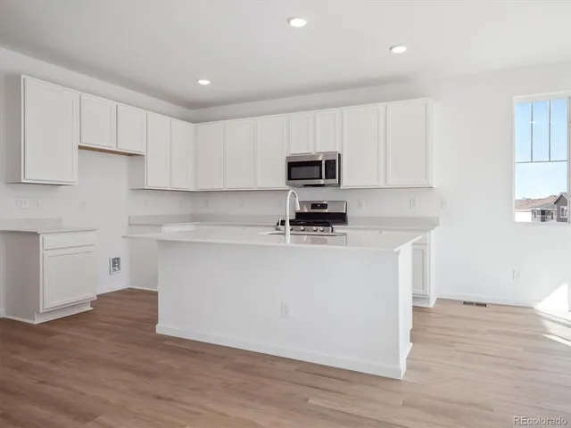 a kitchen with kitchen island a white counter top space cabinets and stainless steel appliances