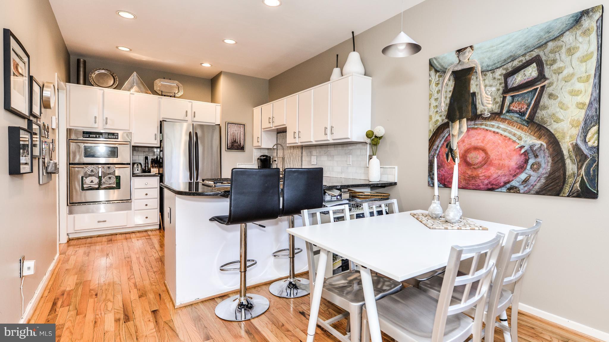 2041 Beacon Place Reston, VA 20191 - Photo 8 of 30 a kitchen with stainless steel appliances kitchen island granite countertop a refrigerator a stove top oven and a dining table with wooden floor