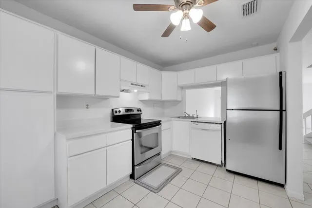 a kitchen with cabinets stainless steel appliances and a chandelier