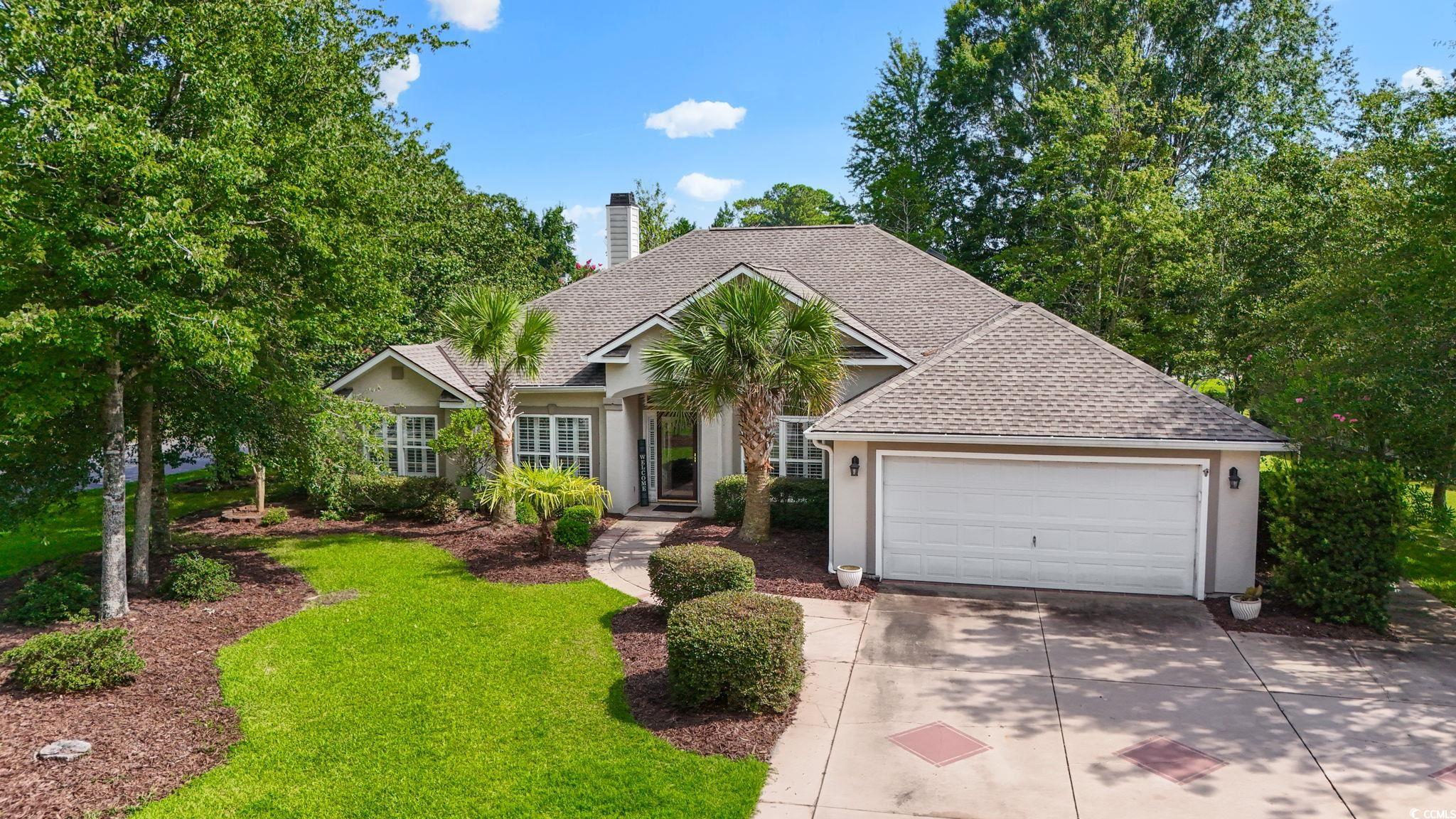 View of front of home with roof with shingles, concrete driveway, stucco siding, and a chimney