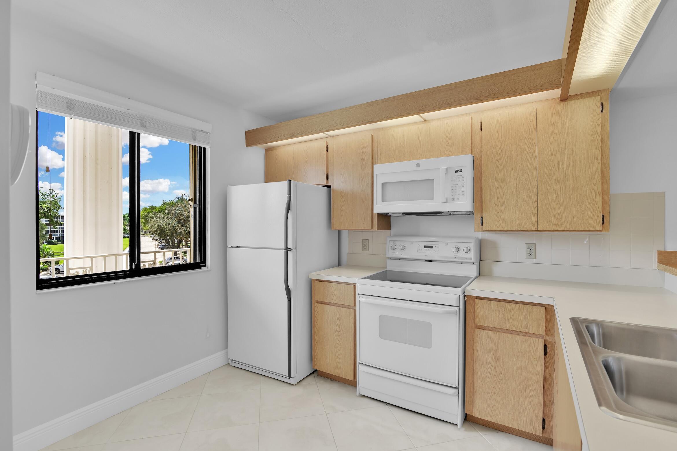 6133 Balboa Circle, Unit 304 Boca Raton, FL 33433 - Photo 11 of 48 a kitchen with a stove a sink and a refrigerator