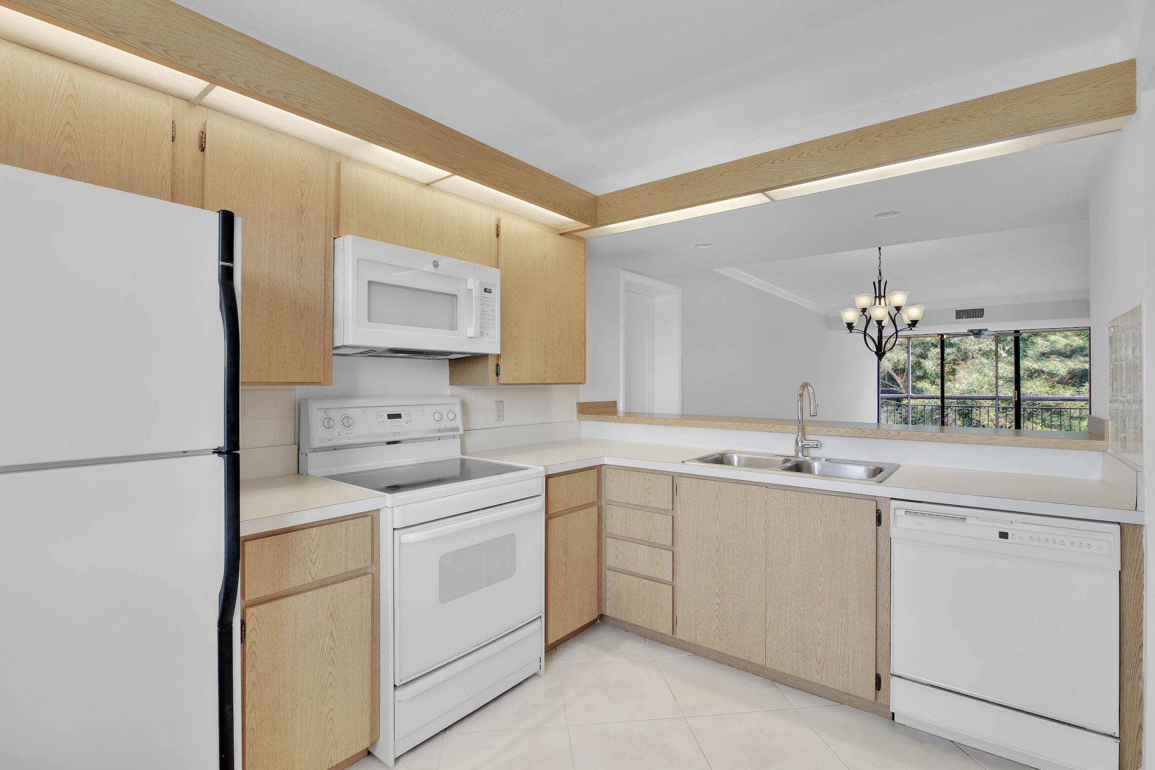 6133 Balboa Circle, Unit 304 Boca Raton, FL 33433 - Photo 12 of 48 a kitchen with white cabinets and white appliances