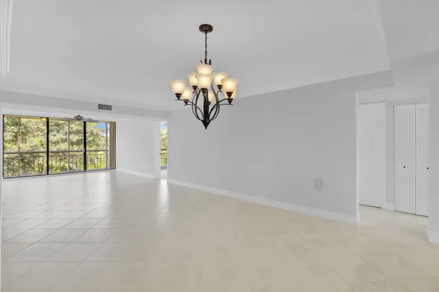 a view of a livingroom with a chandelier fan and windows