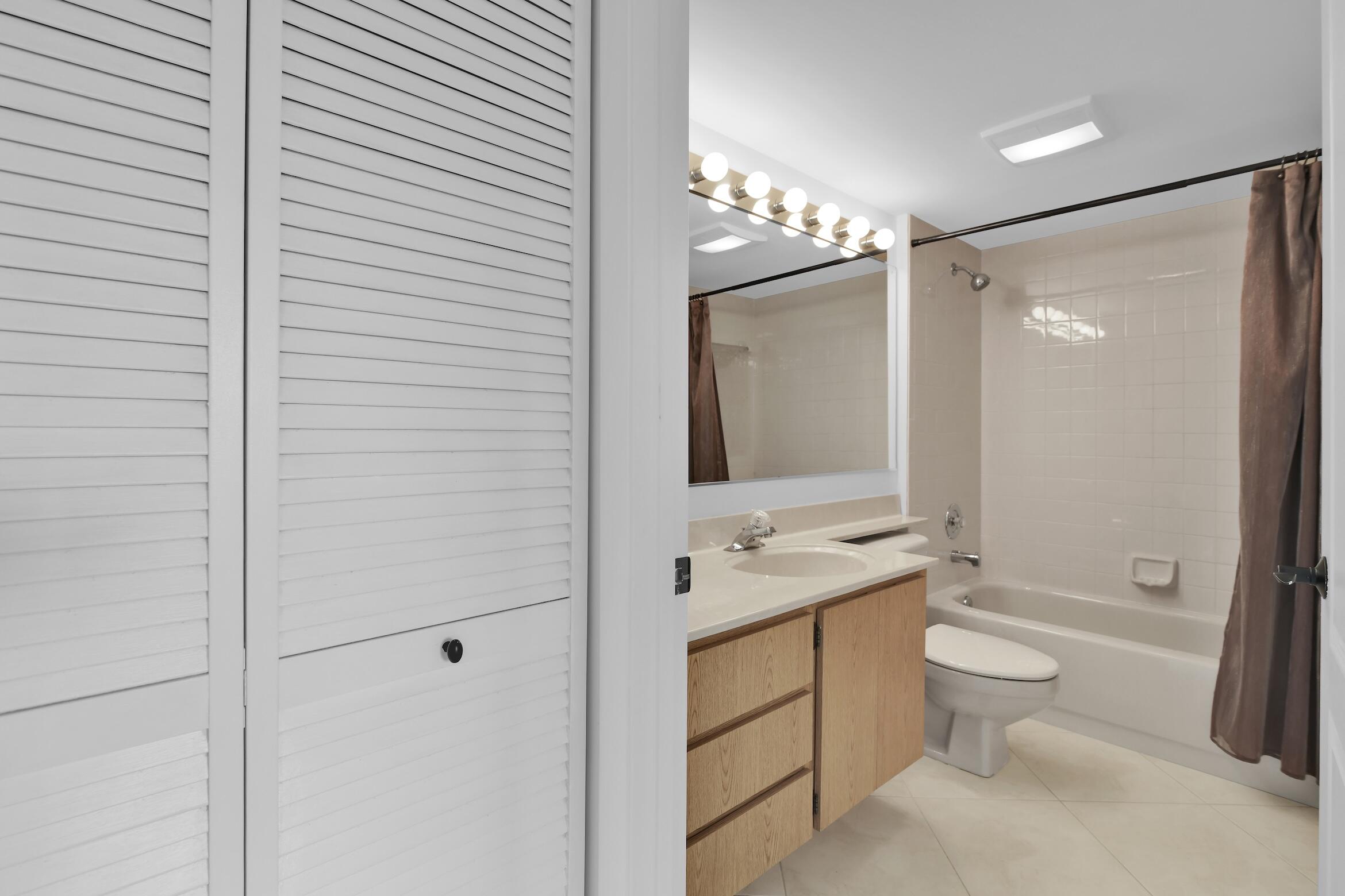 6133 Balboa Circle, Unit 304 Boca Raton, FL 33433 - Photo 40 of 48 a bathroom with a double vanity sink toilet mirror and shower