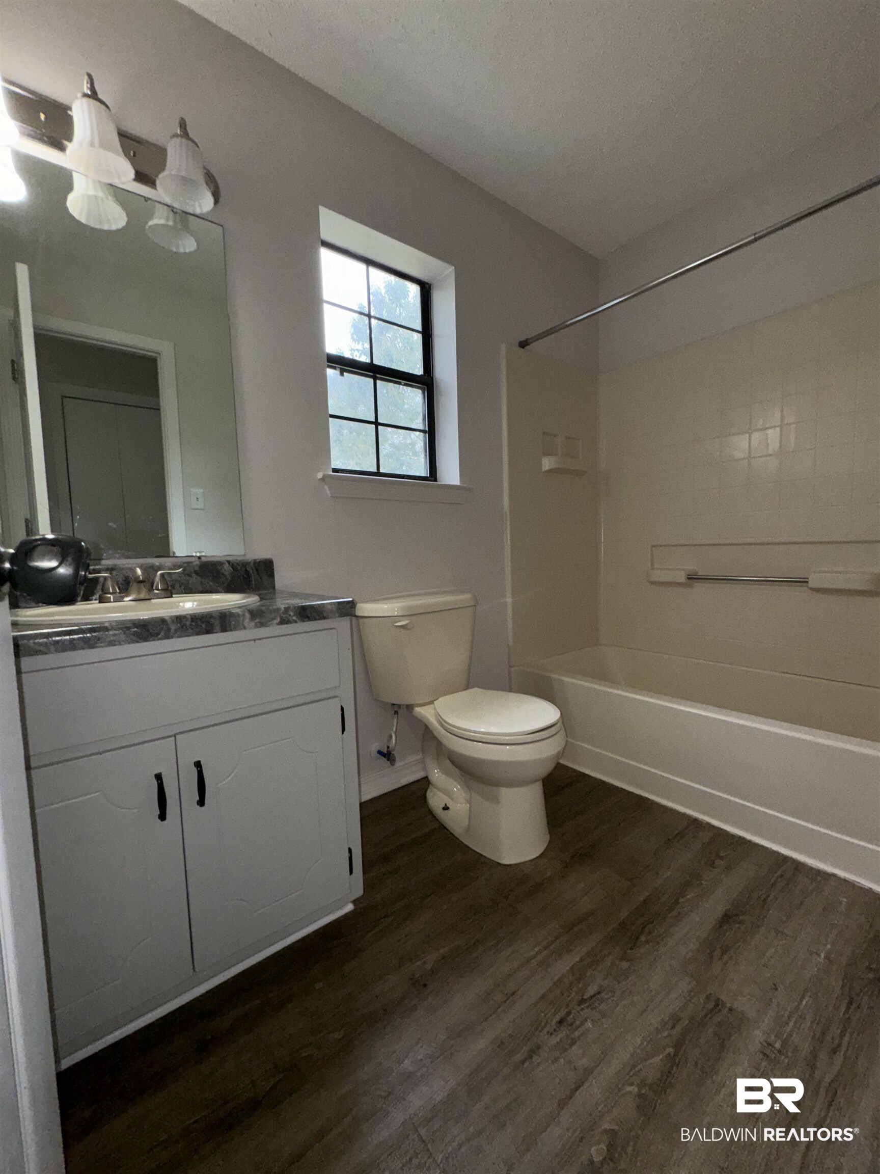 70 Plum Street Uriah, AL 36480 - Photo 19 of 36 Full bathroom with a textured ceiling, washtub / shower combination, hardwood / wood-style floors, vanity, and toilet