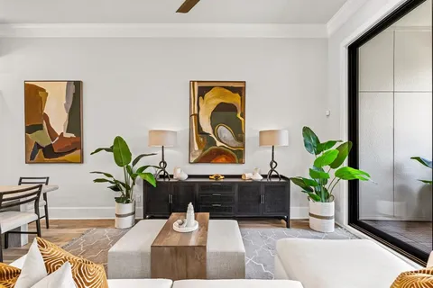 a living room with painting on the wall and a potted plant