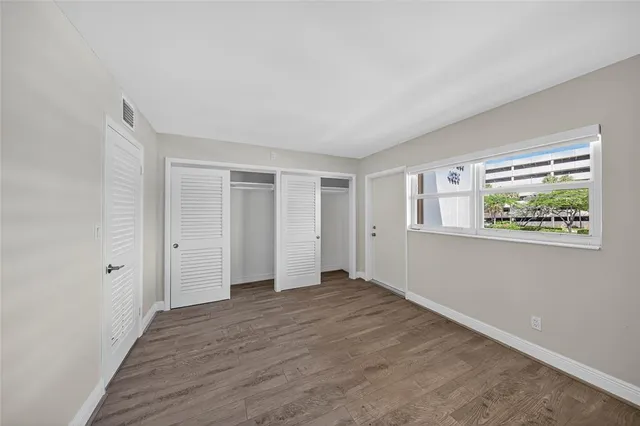a view of an empty room with closet and a window