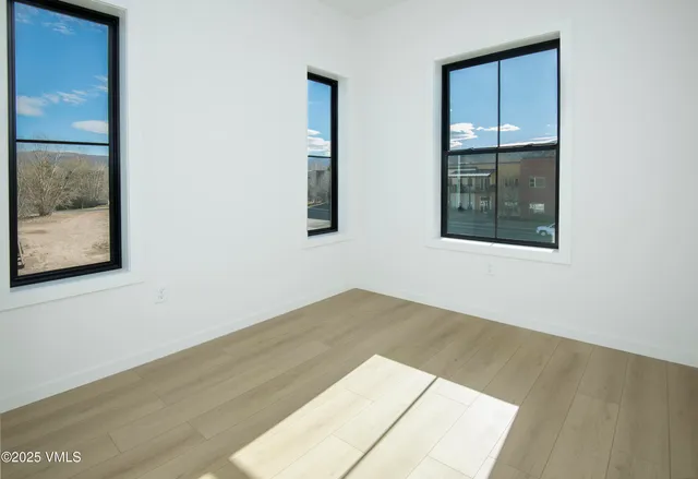 a view of an empty room with wooden floor and a window