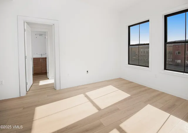 a view of an empty room with wooden floor and entryway