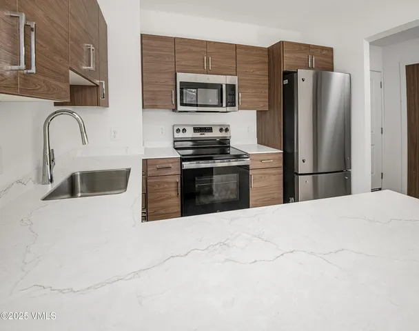 a kitchen with stainless steel appliances granite countertop a refrigerator sink and stove