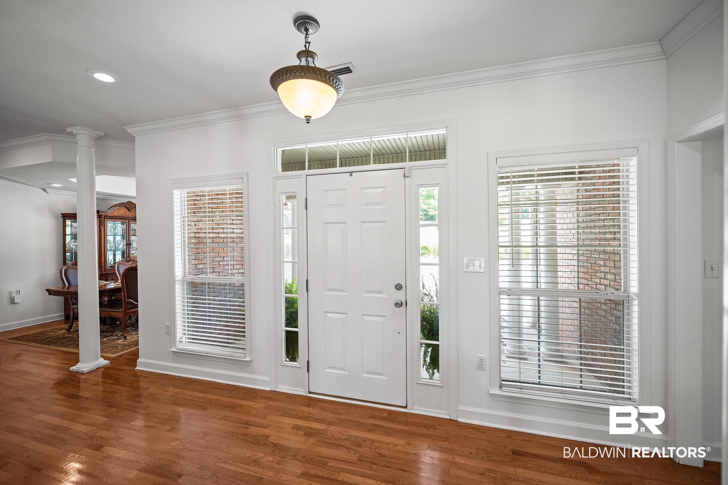 197 Morning Ridge Road Monroeville, AL 36460 - Photo 4 of 51 Bright entry featuring wood-finish flooring, a white paneled entry door with sidelights and transom window, and a decorative ceiling light fixture