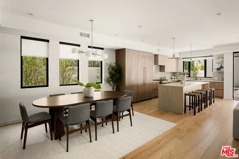 a kitchen with kitchen island granite countertop a table chairs sink and cabinets