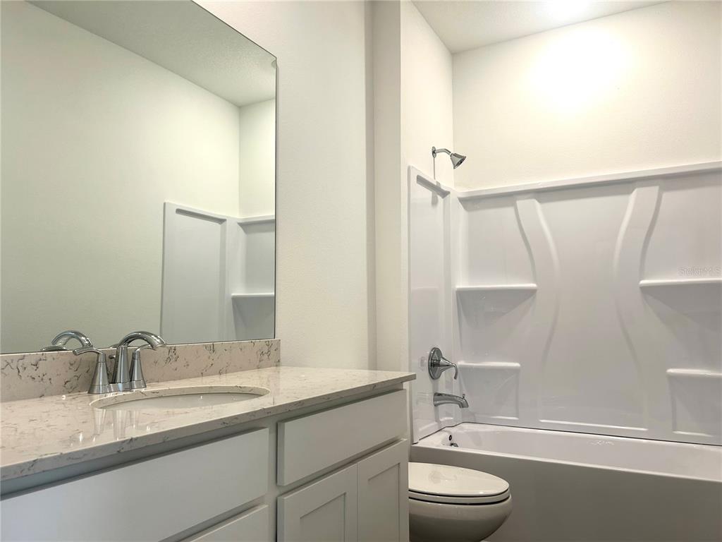 4693 Southwest 83rd Loop Ocala, FL 34476 - Photo 23 of 25 a bathroom with a granite countertop sink toilet a large mirror a shower and vanity