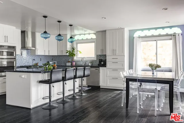 a kitchen with stainless steel appliances granite countertop a sink a stove and chairs