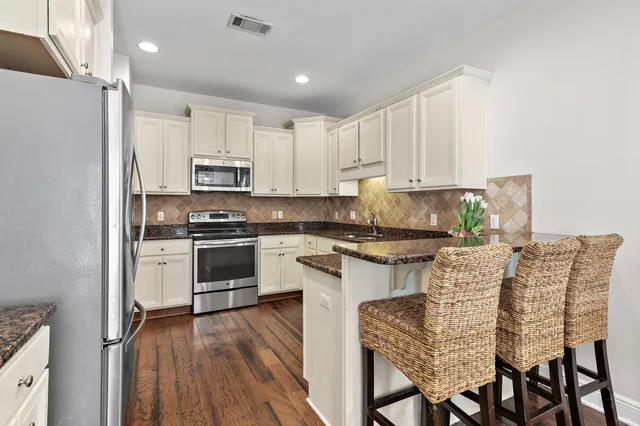 a kitchen with stainless steel appliances granite countertop a white cabinets and wooden floor