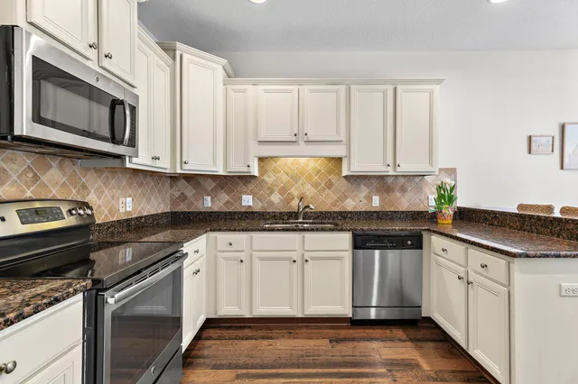 a kitchen with granite countertop white cabinets stainless steel appliances and a sink
