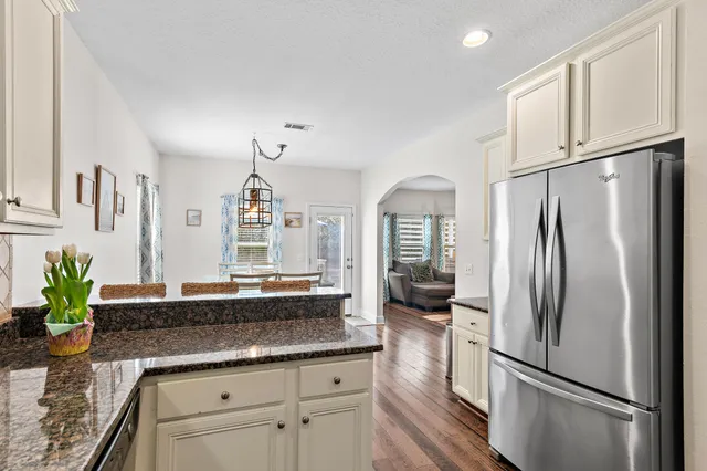 a kitchen with stainless steel appliances granite countertop a refrigerator a sink a stove and white cabinets