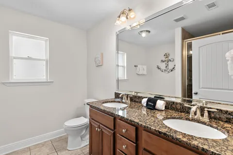 a bathroom with a granite countertop sink toilet and mirror