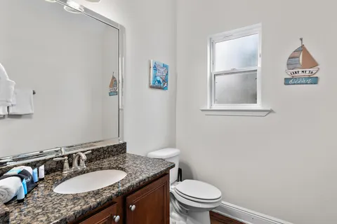 a bathroom with a granite countertop sink a toilet and a mirror