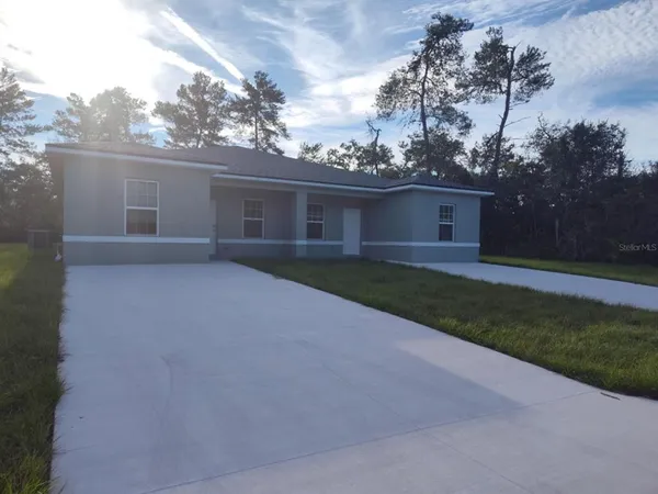 front view of house with yard and trees in the background