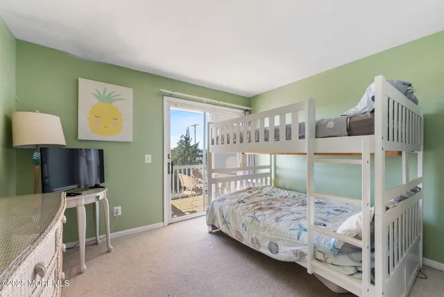 a bedroom with a bed wooden floor and a large window