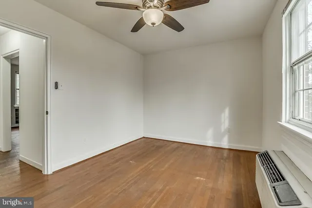 an empty room with wooden floor chandelier fan and windows