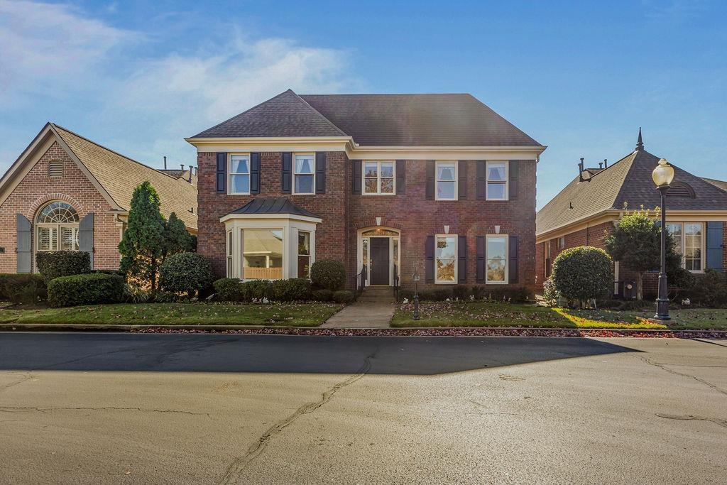 a front view of a house with yard and parking