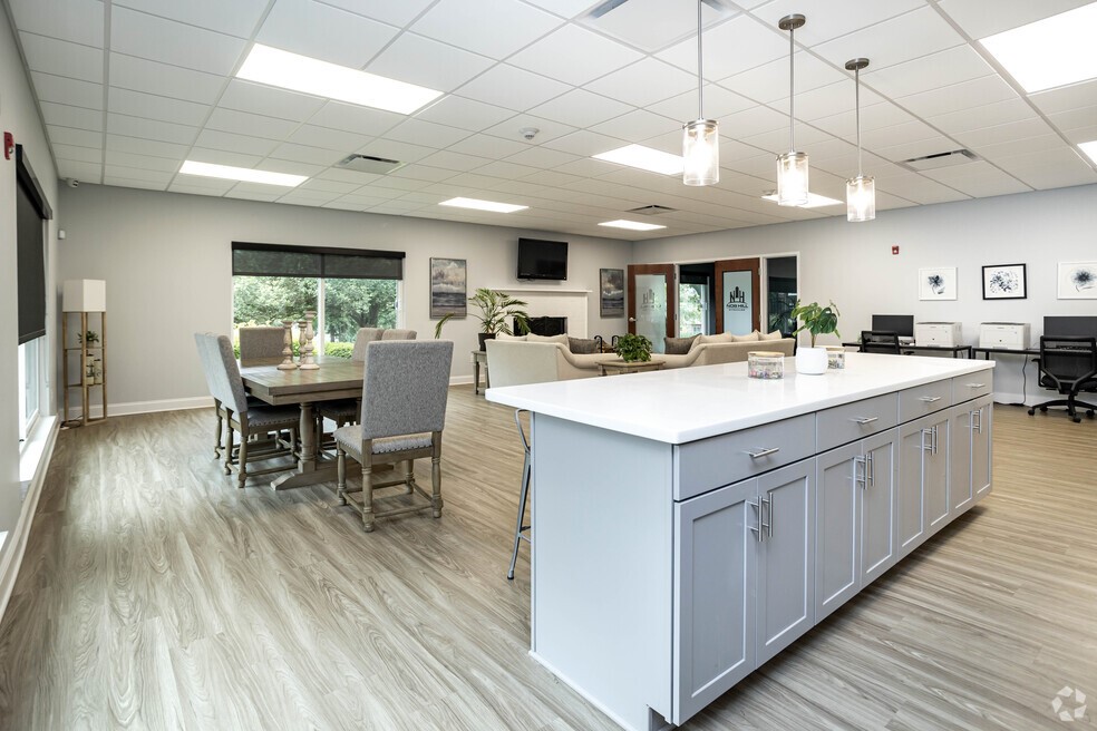 101 Lafayette Road Syracuse, NY 13205 - Photo 22 of 25 a large white kitchen with a large island in the center windows a sink dishwasher a dining table and chairs with wooden floor