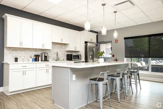 a kitchen with stainless steel appliances a table chairs refrigerator and microwave