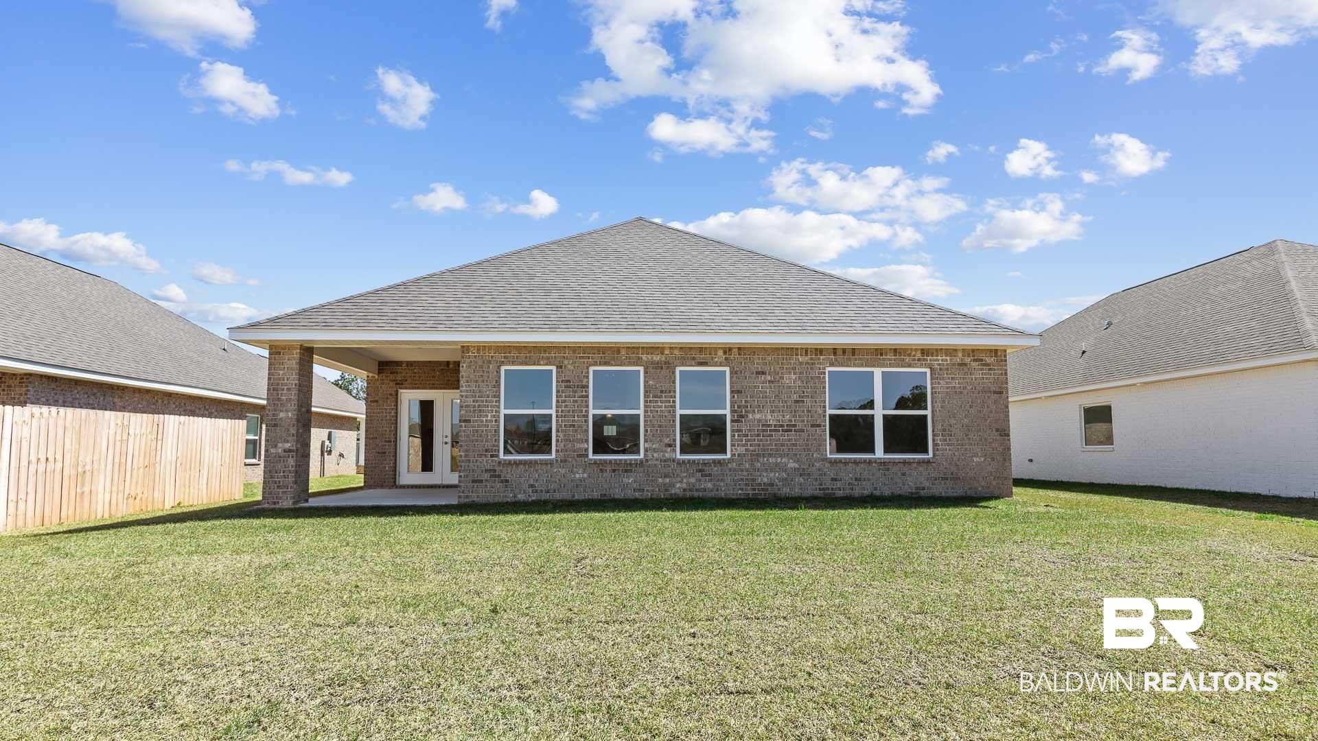 12931 Grand Rpds Road Fairhope, AL 36532 - Photo 3 of 33 Rear view of house with brick siding, roof with shingles, a lawn, and fence