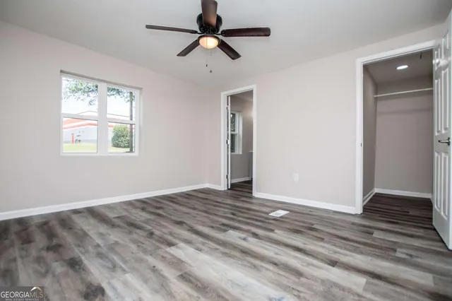 a view of an empty room with window and a ceiling fan