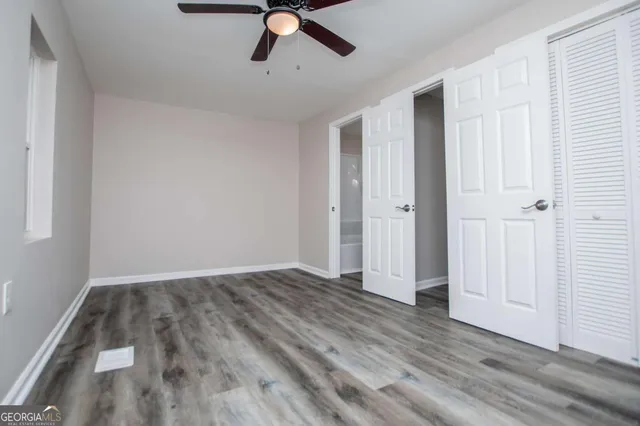 an empty room with wooden floor ceiling fan and window