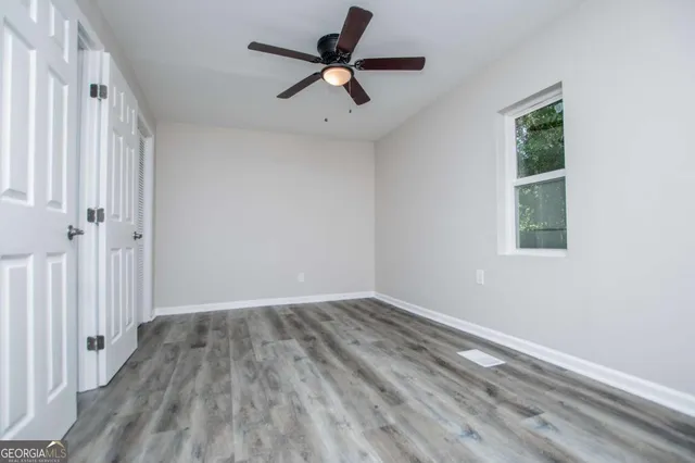 a view of a room with wooden floor fan and windows