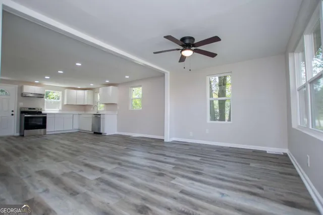 a view of empty room with wooden floor and fan