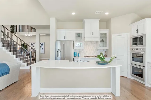 a large white kitchen with stainless steel appliances kitchen island granite countertop a sink and cabinets