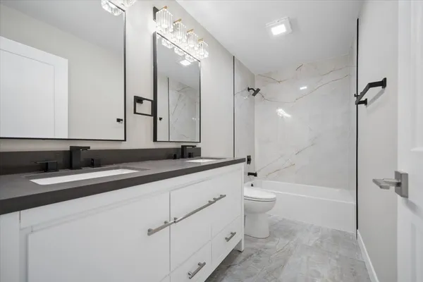 a bathroom with a double vanity sink toilet mirror and bathtub