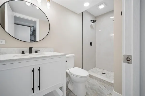 a bathroom with a toilet a sink a shower a mirror and vanity