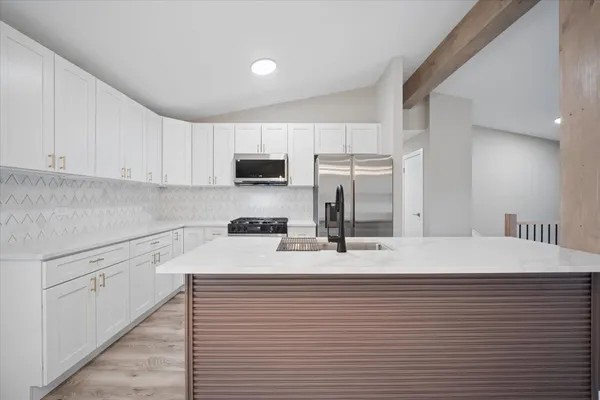 a kitchen with kitchen island granite countertop a sink a stove and refrigerator