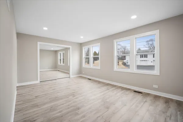 a view of an empty room with a window and wooden floor