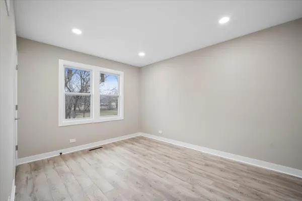 a view of empty room with wooden floor and fan