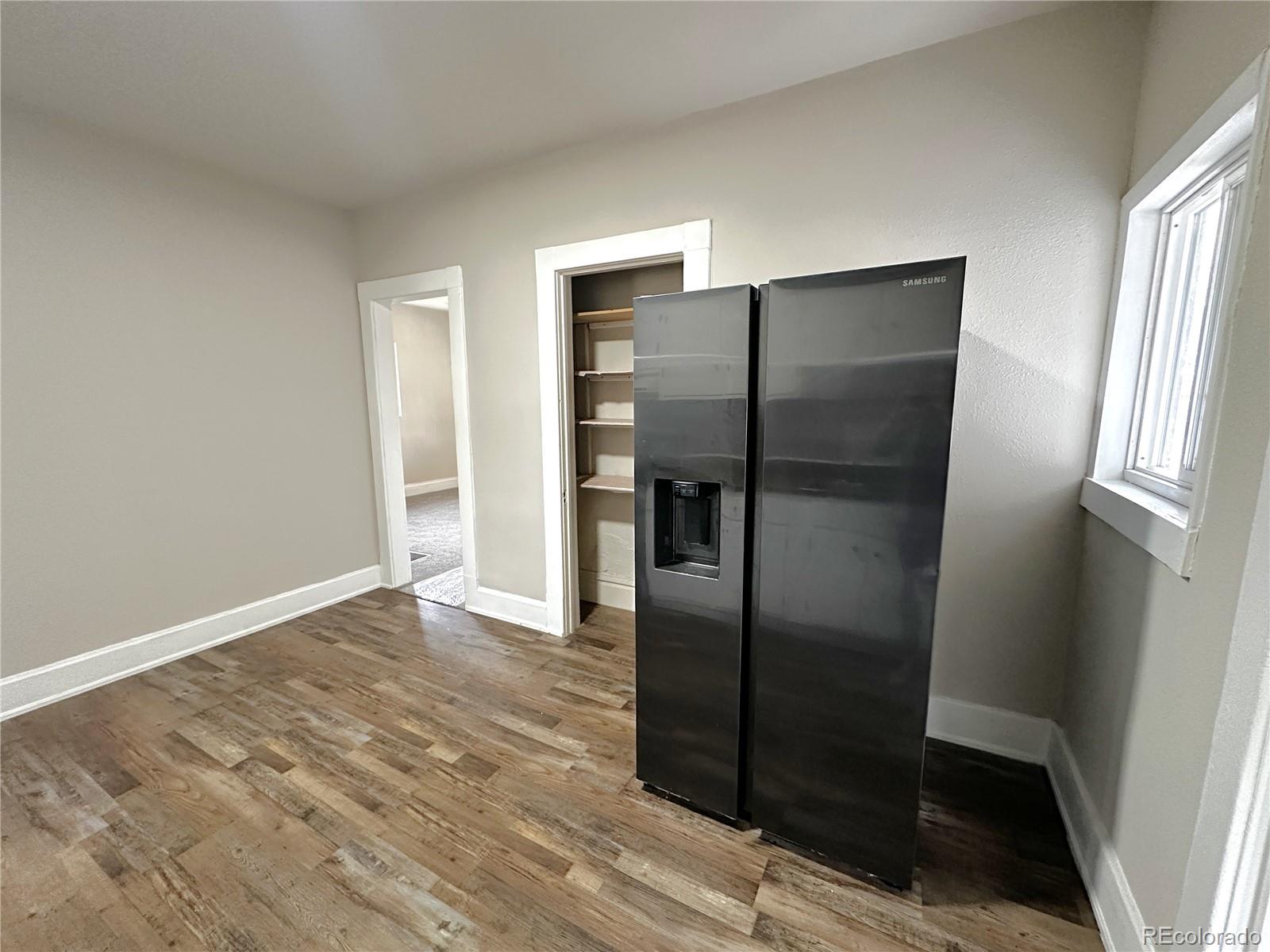 672 4th Street Limon, CO 80828 - Photo 15 of 28 a view of a refrigerator in kitchen and an empty room with wooden floor