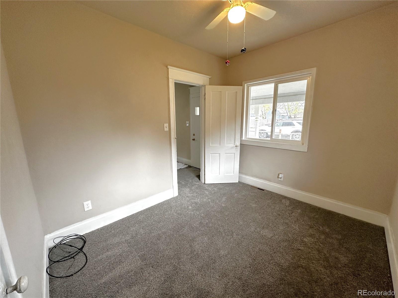 672 4th Street Limon, CO 80828 - Photo 10 of 28 an empty room with a chandelier fan and windows