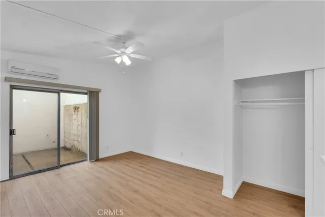 a view of an empty room with wooden floor and a ceiling fan